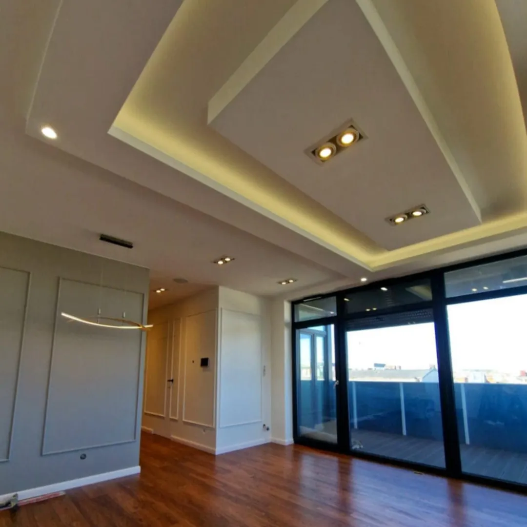 Nowoczesny podwieszany sufit z wbudowanymi downlightami podkreślający strefę wypoczynkową w salonie w stylu modern classic